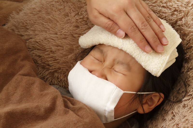 ホメオパシー インフルエンザ 子供 子供が熱を出してマスクをして頭にタオルをあてている