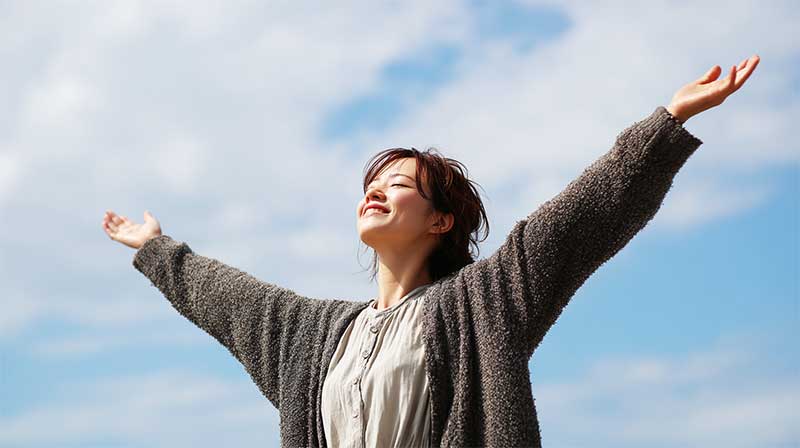 笑顔の健康的な女性ホメオパシーでインナーチャイルドが癒やされている 空にむかって手を広げている女性