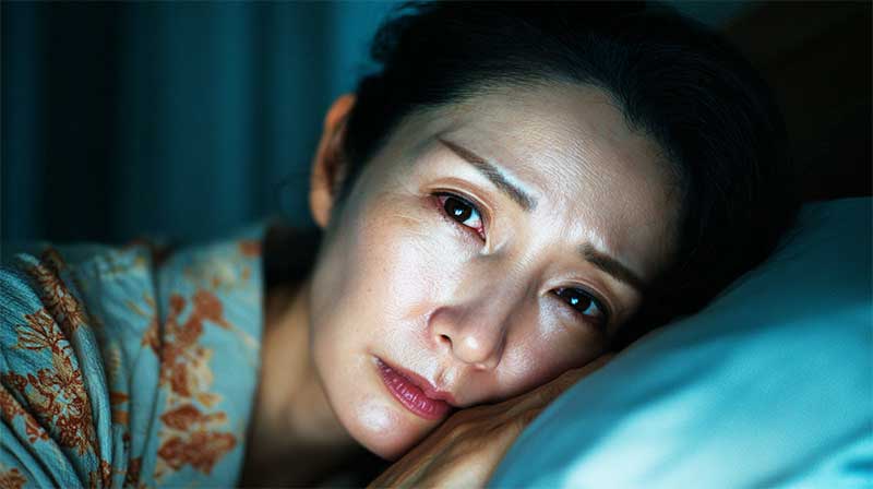 ホメオパシー 更年期 不眠 布団で起きている女性がこちらをみている汗ばんでいる