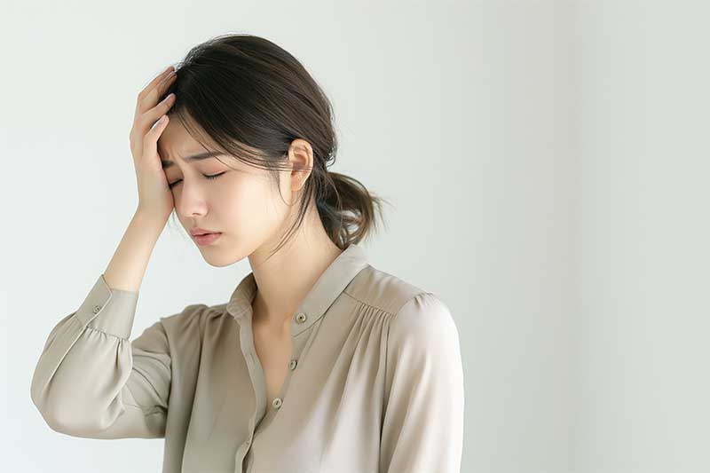 ホメオパシー レメディー ナトルム ネイチュミュア Nat-m 頭痛で片手で頭を押さえる女性