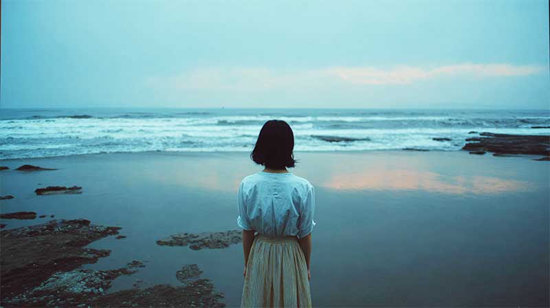 悲しそうに海を見ている女性の後ろ姿