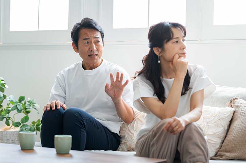夫婦が話し合いでうまくいっていない、女性は夫を背にそっぽをむいている