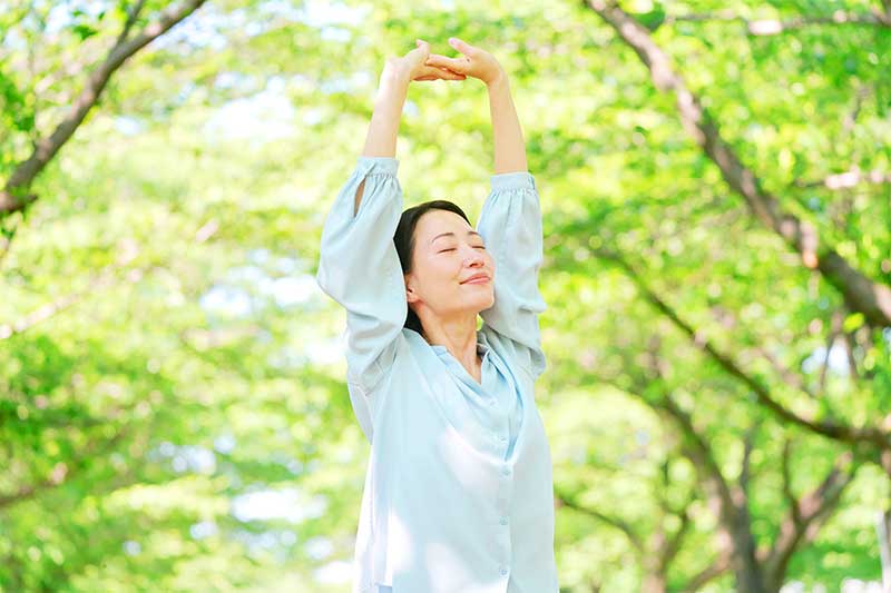 緑の中で伸びをしている女性