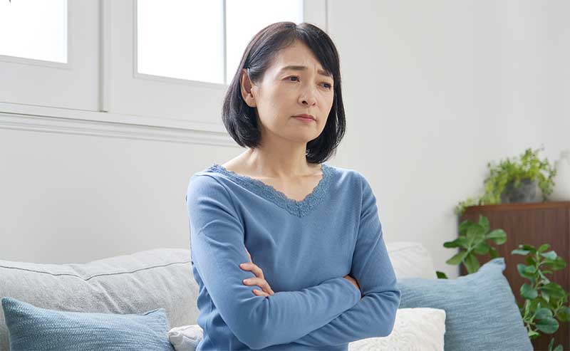 ホメオパシー 更年期 関節痛 腕をくんで悩む女性